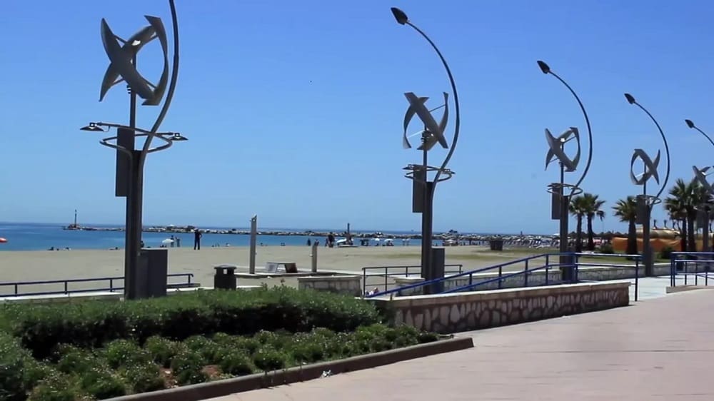 A panoramic view of Huelin beach with people enjoying a sunny day.