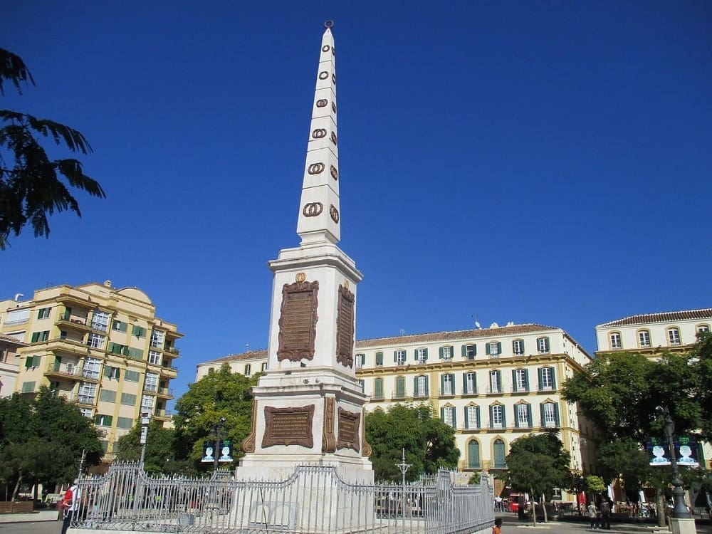 The bustling Plaza de la Merced in Malaga, filled with people enjoying the local cuisine at various restaurants and cafes.