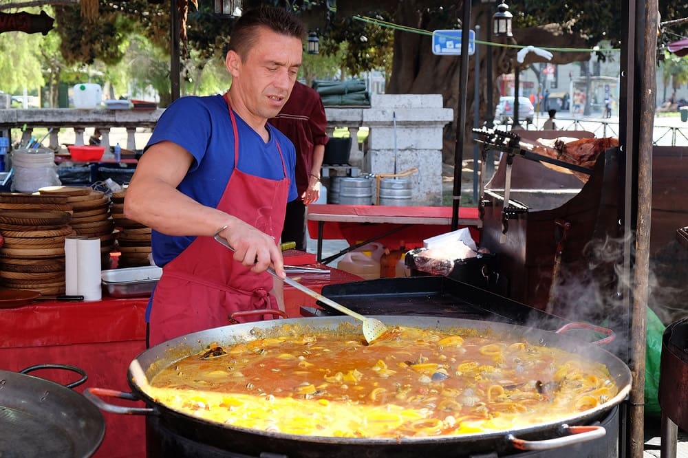 Man cooking a big and delicious paella.