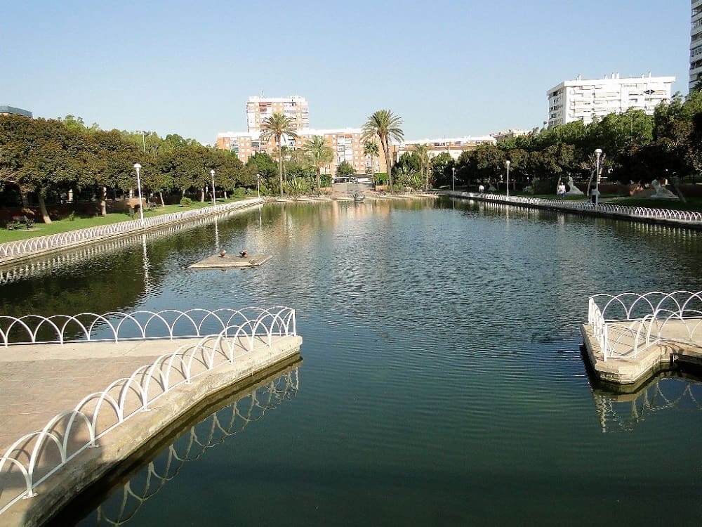 A panoramic view of Parque Del Oeste with lush green trees, art installations, and visitors enjoying the serene environment