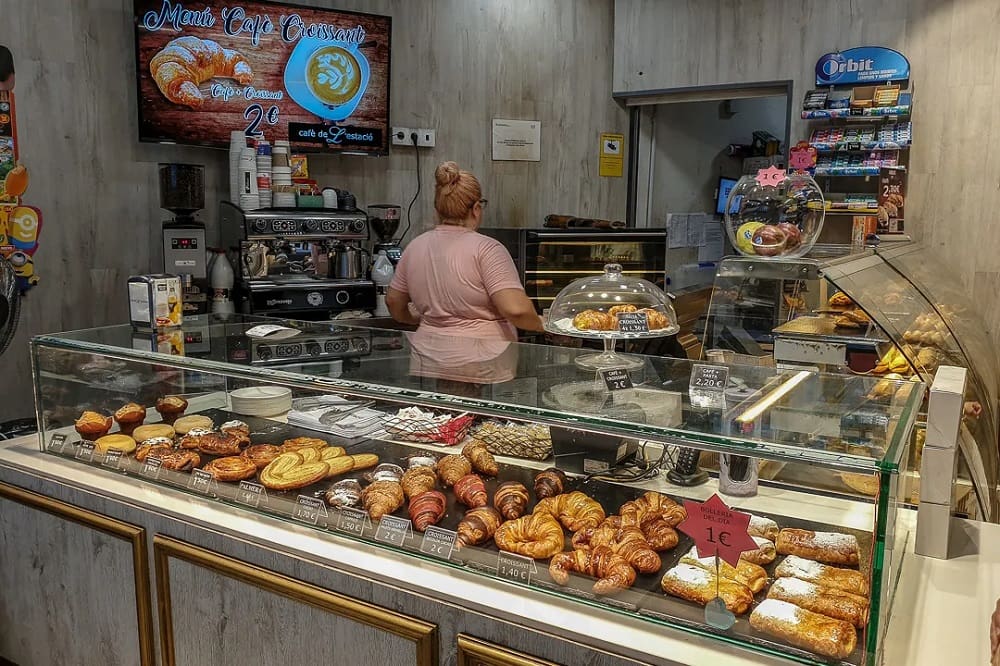 Assorted traditional Spanish pastries on a rustic wooden table, with a backdrop of a Spanish countryside